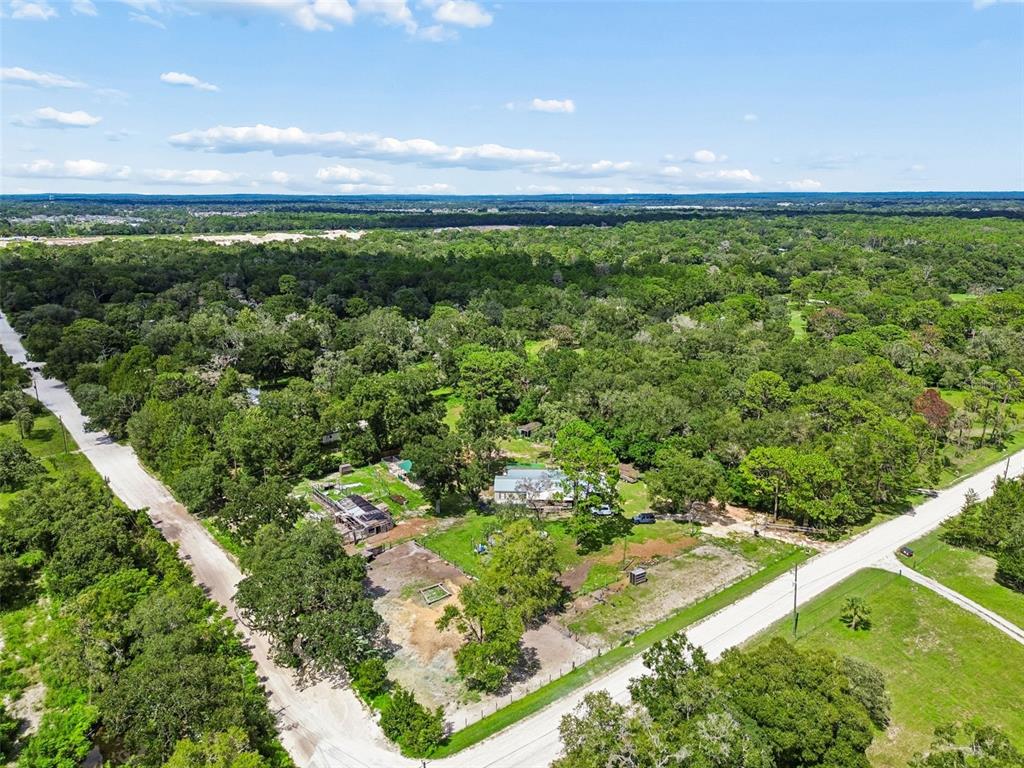 An aerial view shows a rural property with a house, outbuildings, and trees between roads — 18020 RIGSBY ROAD, SPRING HILL, FL