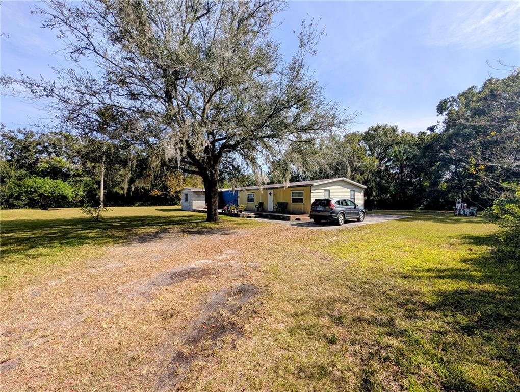 A yellow single-story house sits on a large, grassy lot with a large oak tree — 8412 PETERSON ROAD, ODESSA, FL