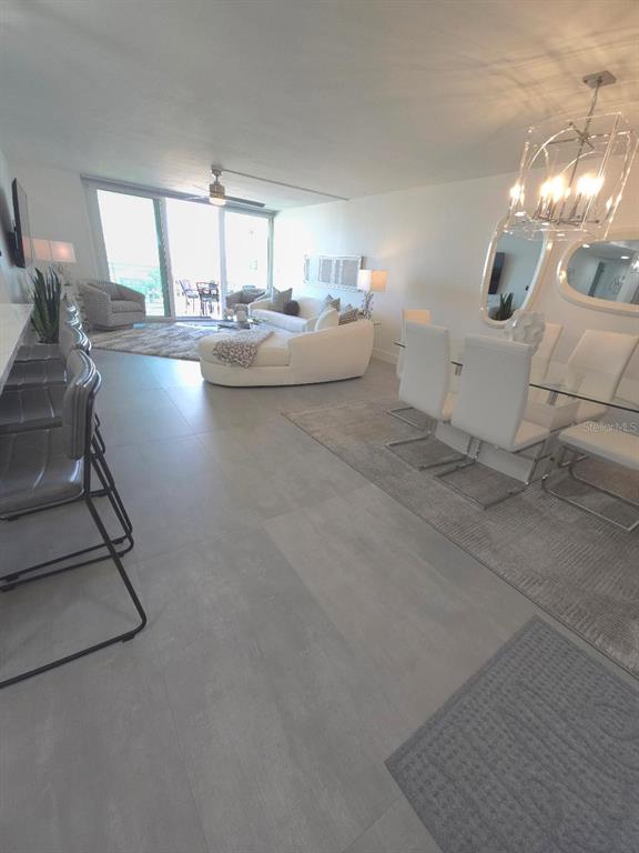 A modern living room features a white sofa, patterned armchairs, a shaggy rug, and balcony access — 675 S GULFVIEW BOULEVARD UNIT 505, CLEARWATER BEACH, FL