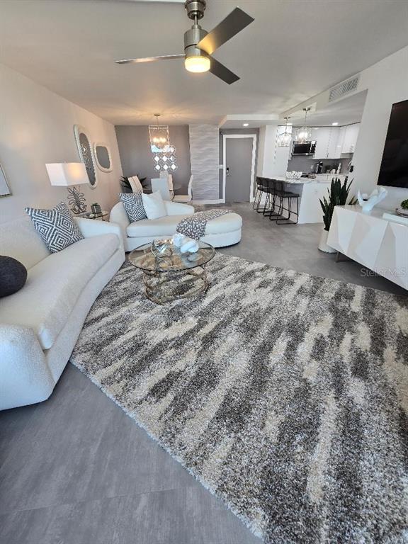An open-concept living and dining area features large floor tiles, white furniture, and a balcony — 675 S GULFVIEW BOULEVARD UNIT 505, CLEARWATER BEACH, FL