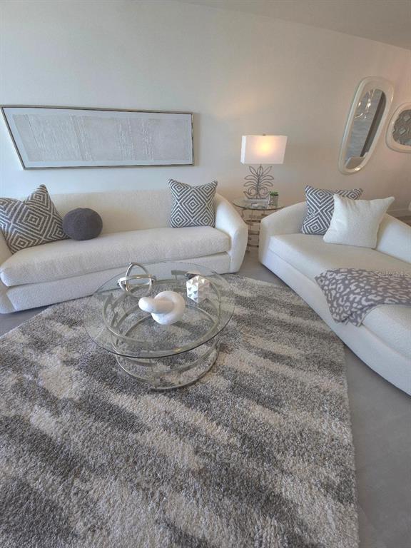 A living room features a white sofa, a patterned rug, and an open-concept kitchen — 675 S GULFVIEW BOULEVARD UNIT 505, CLEARWATER BEACH, FL