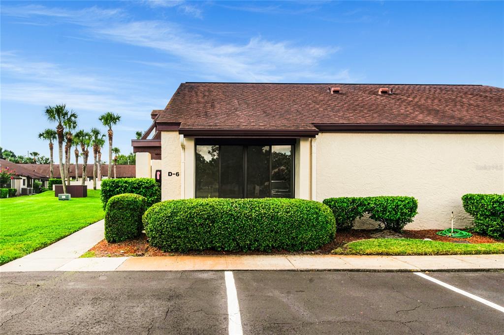 A single-story building with a brown shingled roof, beige stucco walls, and a parking space — 101 GRAND PLAZA DRIVE UNIT D60, ORANGE CITY, FL