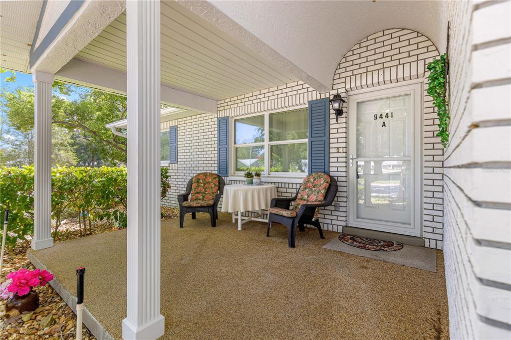 A covered front porch features white brick walls, two chairs, a small table, and columns — 9441 SW 85TH TERRACE UNIT A, OCALA, FL