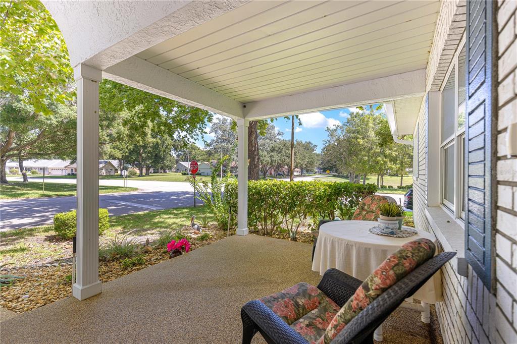 A covered front porch features a concrete floor, a small table, and a wicker chair — 9441 SW 85TH TERRACE UNIT A, OCALA, FL