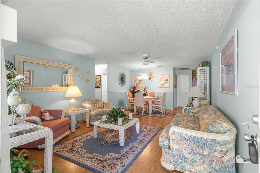 A living and dining area with light blue walls, tile floors, and floral-patterned furniture — 9441 SW 85TH TERRACE UNIT A, OCALA, FL