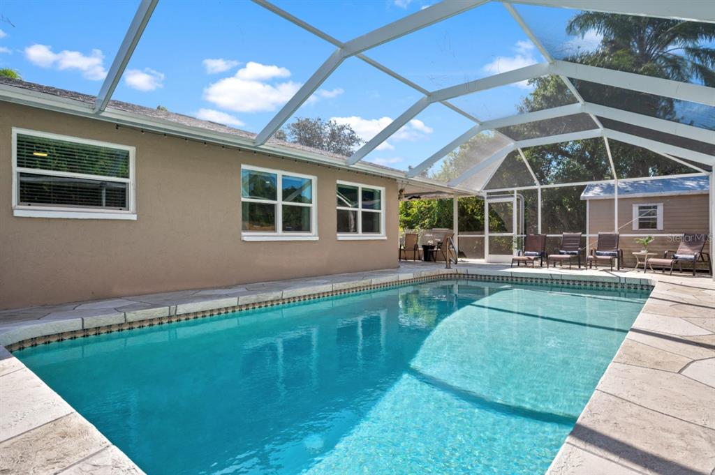 A screened-in pool patio features stone-patterned concrete flooring and three lounge chairs — 874 ACADIA ROAD, VENICE, FL