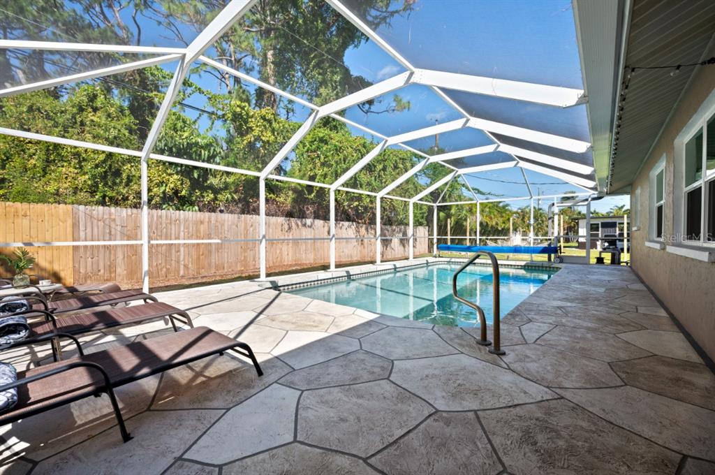 A rectangular swimming pool is enclosed by a screened lanai with a stone-patterned patio — 874 ACADIA ROAD, VENICE, FL