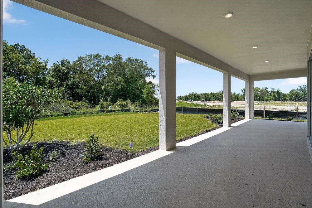 A modern kitchen features white cabinetry, a large island with a sink, and wood flooring — 13333 STABLE PLACE, PARRISH, FL