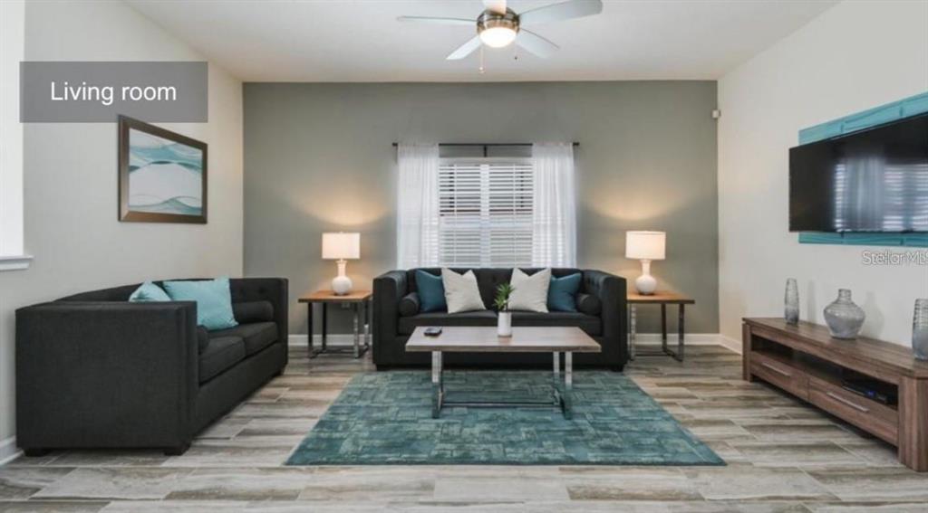 A living room features dark sofas, a wooden coffee table, and a wall-mounted television — 1592 SLICE WAY, DAVENPORT, FL