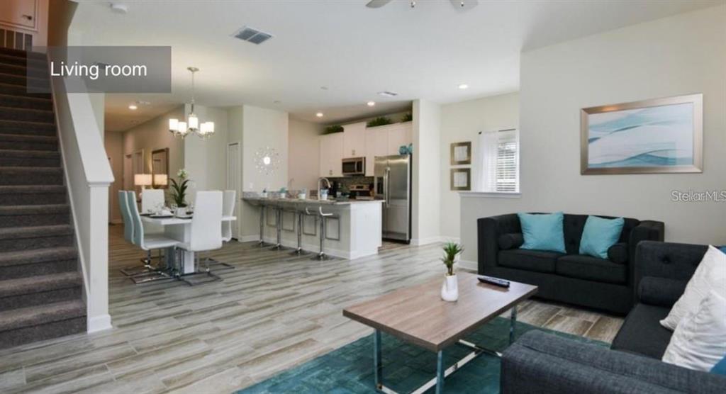 An open-concept living room and kitchen featuring wood-look tile flooring and modern furniture — 1592 SLICE WAY, DAVENPORT, FL