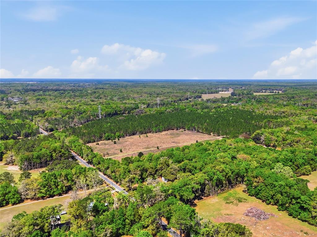 An aerial view shows a rural landscape with a paved road, trees, and open fields — 11791 SW 143RD STREET SW, ARCHER, FL