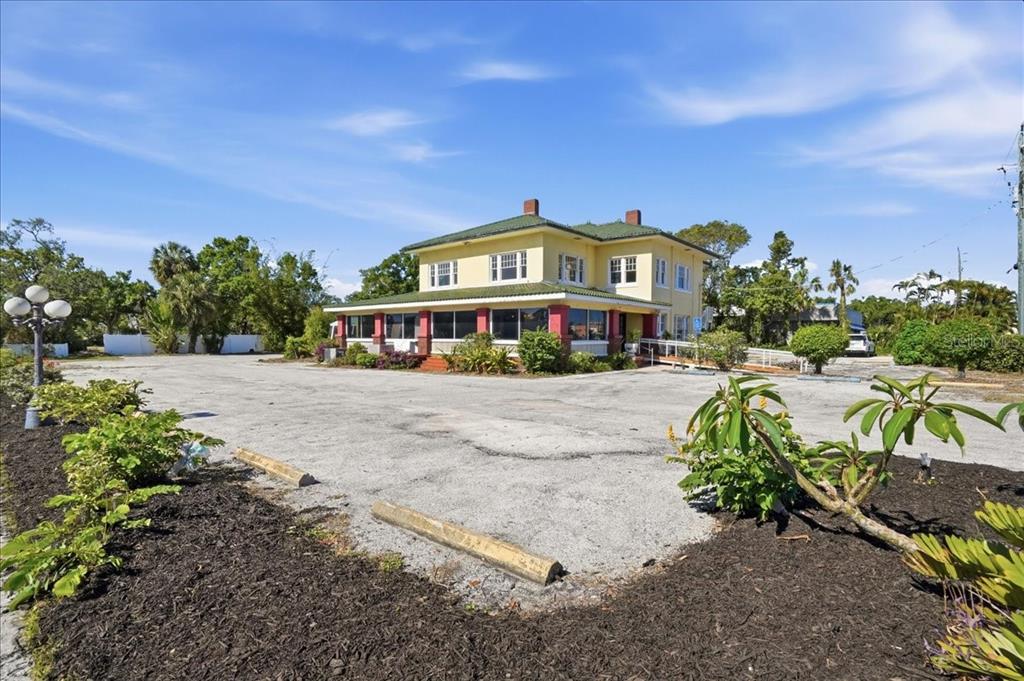 A yellow two-story building with a green roof sits behind a large paved parking lot — 337 US-41 BUS., PALMETTO, FL