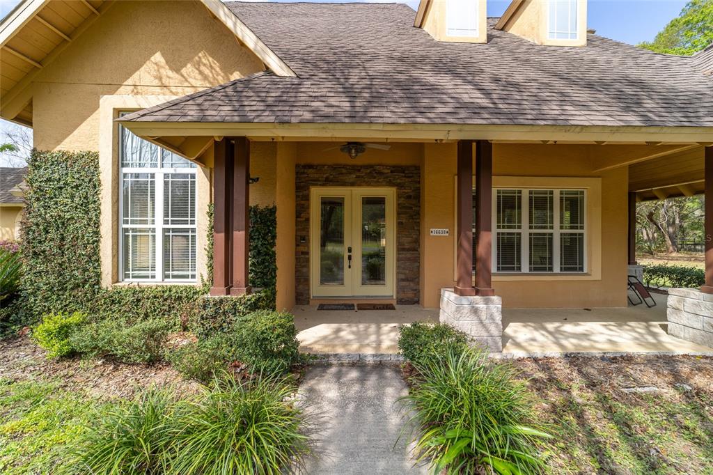 The exterior of a house features a covered porch, stone accents, and double glass doors — 16638 N HIGHWAY 329, REDDICK, FL