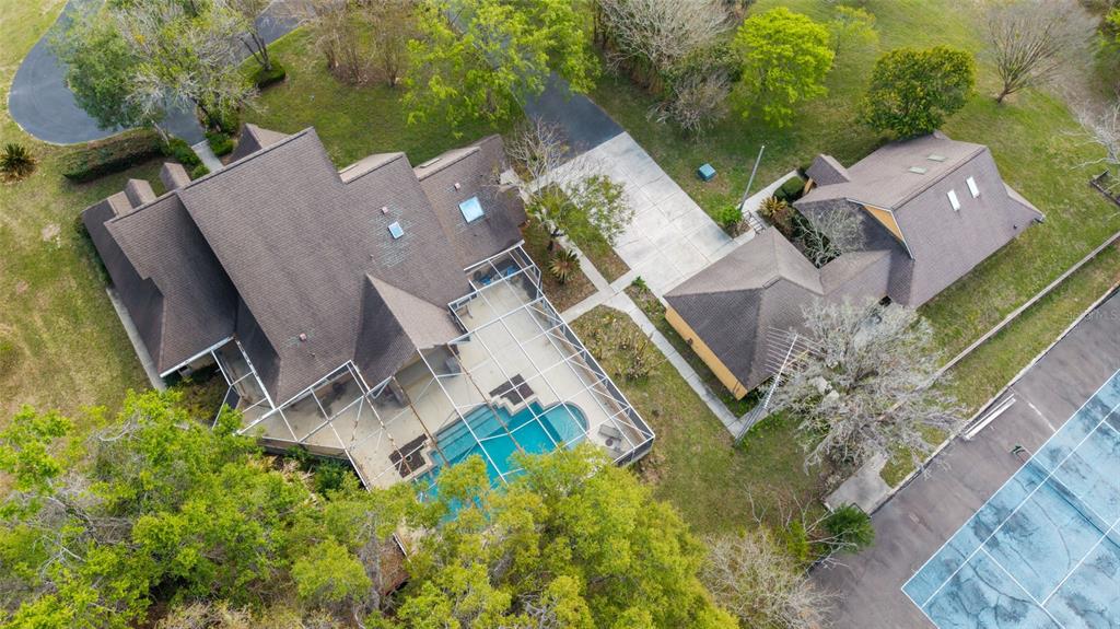 An aerial view shows a house with a pool enclosure, detached garage, and tennis court — 16638 N HIGHWAY 329, REDDICK, FL