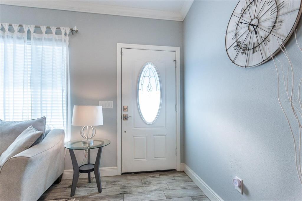 An entryway features a white front door, a glass side table with a lamp, and a clock — 8 SEQUOIA DRIVE COURSE, OCKLAWAHA, FL