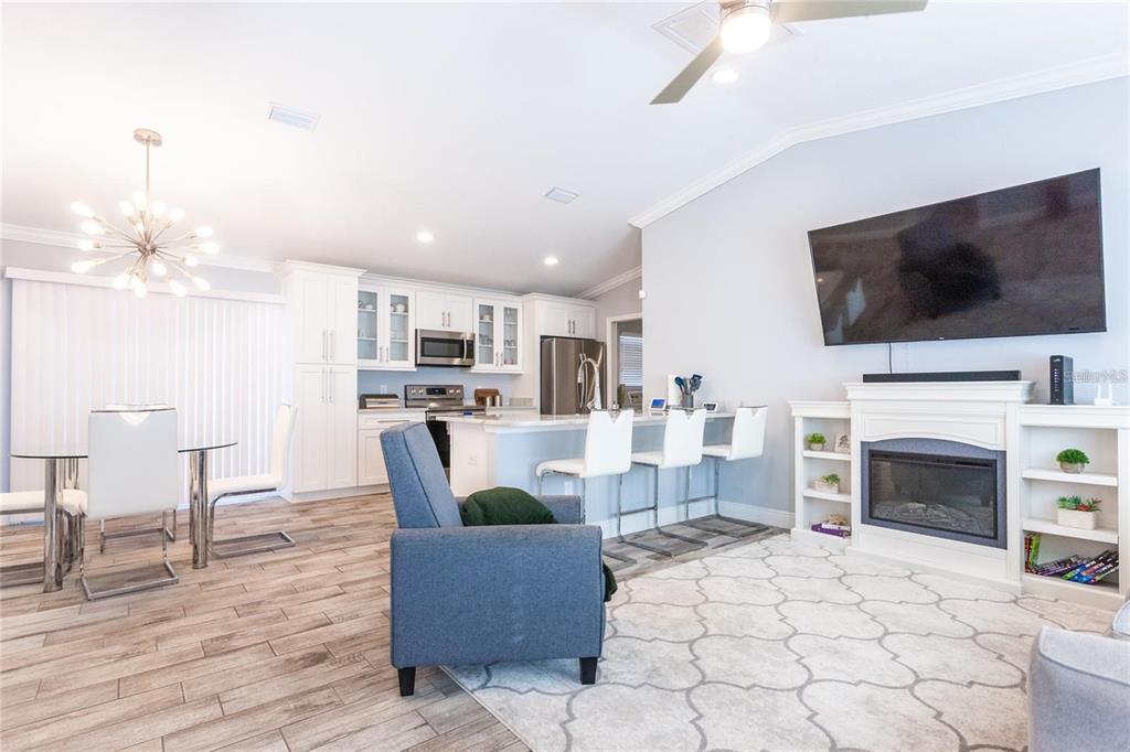 An open-concept living area features a kitchen with white cabinetry, a fireplace, and dining space — 8 SEQUOIA DRIVE COURSE, OCKLAWAHA, FL
