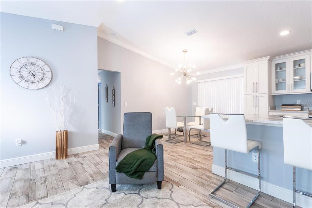 A gray armchair sits on a rug in an open-concept dining and kitchen area — 8 SEQUOIA DRIVE COURSE, OCKLAWAHA, FL