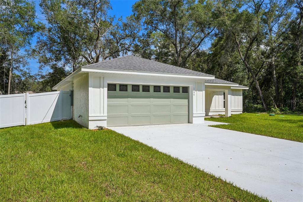 A single-story house with a light green garage door, white siding, and a concrete driveway — 1194 W VIRGINIS DRIVE, CITRUS SPRINGS, FL