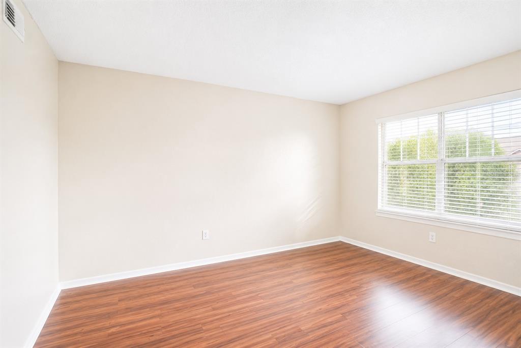 An empty bedroom features beige walls, wood-look laminate flooring, and a window with white blinds — 2208 ANTIGUA PLACE UNIT 932, KISSIMMEE, FL