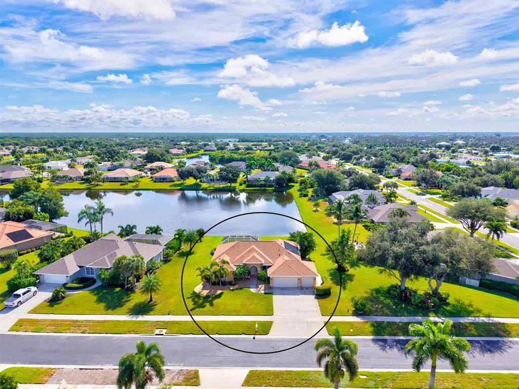 A screened-in lanai features a swimming pool with a tiled water feature overlooking a lake — 203 LAKE VICTORIA COURT, ENGLEWOOD, FL