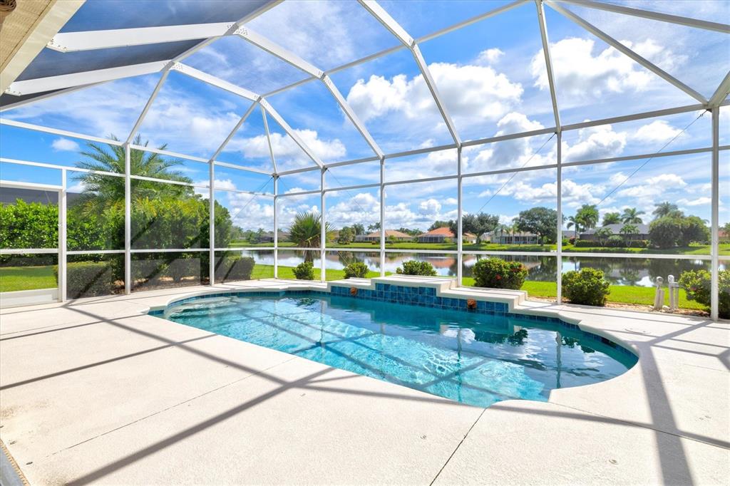 A single-story house with a tan exterior, three-car garage, and palm trees in the yard — 203 LAKE VICTORIA COURT, ENGLEWOOD, FL