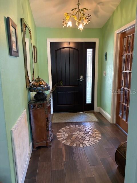 A foyer features a dark wood front door, tile flooring, and a decorative chandelier — 7561 HOLLY LAKE LANE, NEW PORT RICHEY, FL