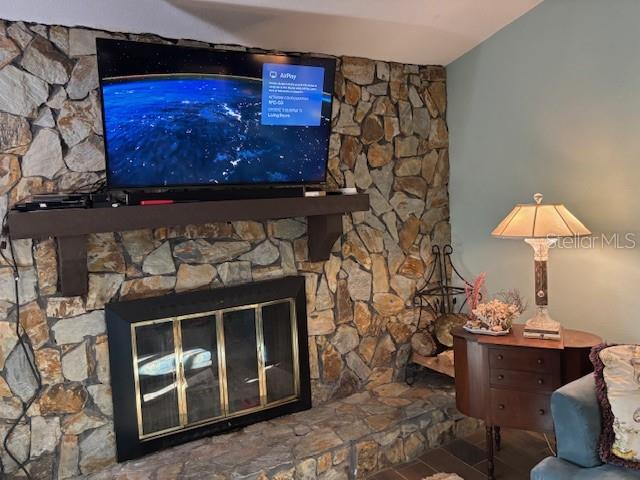 A stone fireplace with a wooden mantel and a mounted television sits in a living room — 7561 HOLLY LAKE LANE, NEW PORT RICHEY, FL