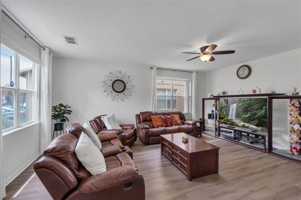 A living room features brown leather sofas, a wooden coffee table, and a large television — 711 KETTERING ROAD, DAVENPORT, FL