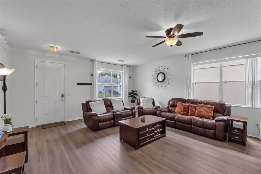 A living room features brown leather furniture, a coffee table, and light wood-look flooring — 711 KETTERING ROAD, DAVENPORT, FL