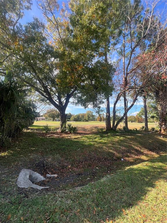 A grassy lot with several large trees overlooks a golf course under a blue sky — 3601 MIDIRON DRIVE, WINTER PARK, FL