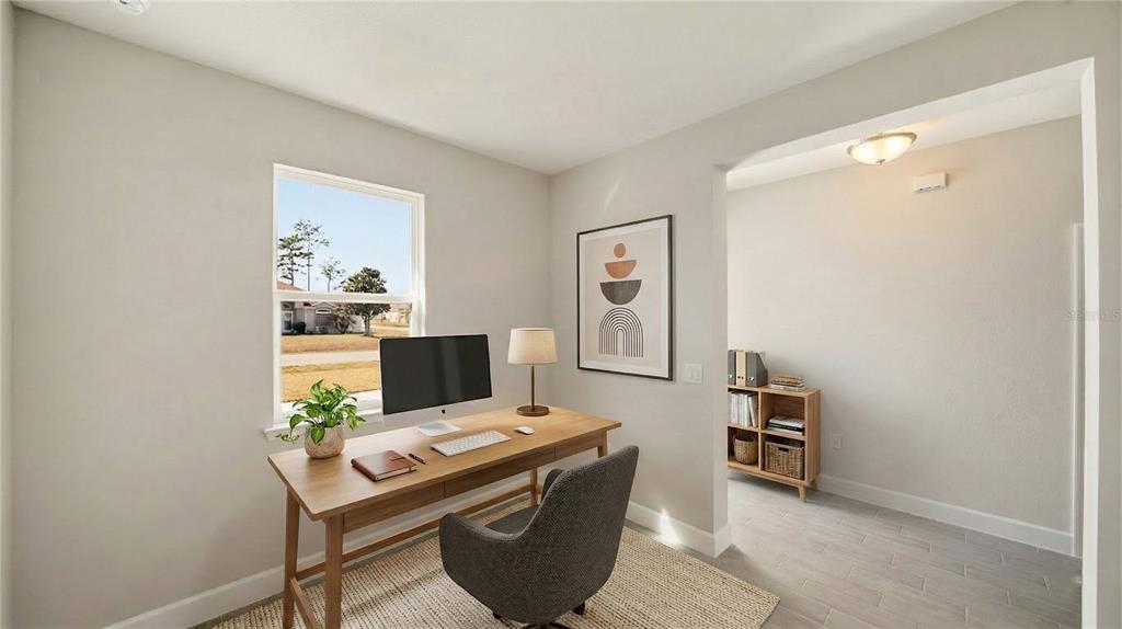 A home office features a wooden desk, a gray chair, and a window view — 34 SEVILLE ORANGE PATH, PALM COAST, FL