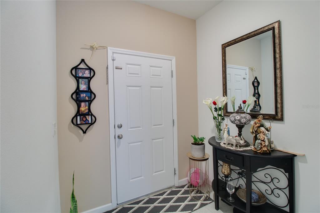 An entryway features a white front door, a black console table with decor, and a mirror — 8732 SPORTSMAN LOOP, GROVELAND, FL