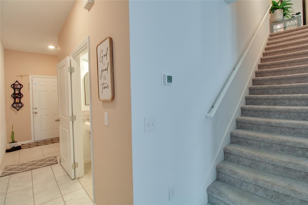 An entryway features tiled flooring, a staircase with gray carpet, and a small powder room — 8732 SPORTSMAN LOOP, GROVELAND, FL