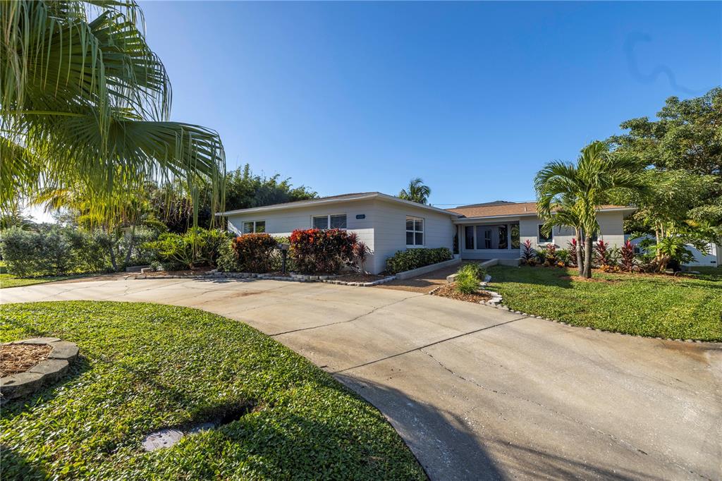 A single-story house with a concrete driveway and palm trees under a clear blue sky — 610 CORDOVA BOULEVARD NE, ST PETERSBURG, FL