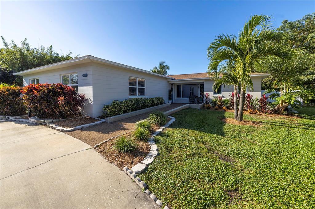 A single-story house with light siding, a concrete driveway, and a palm tree in front — 610 CORDOVA BOULEVARD NE, ST PETERSBURG, FL