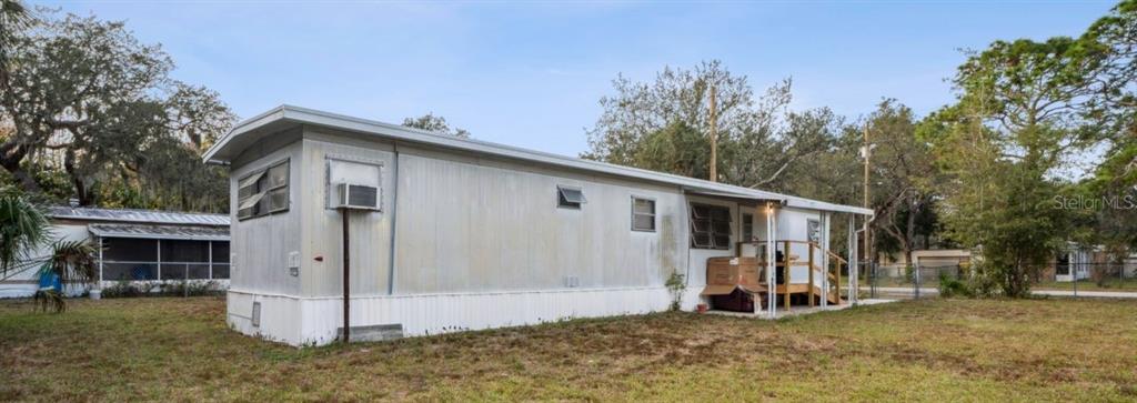 A side view of a single-wide mobile home with metal siding and a small wooden porch — 9300 KIOWA DR, NEW PORT RICHEY, FL