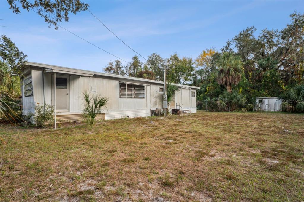 A single-story mobile home with metal siding sits on a large, grassy lot — 9300 KIOWA DR, NEW PORT RICHEY, FL