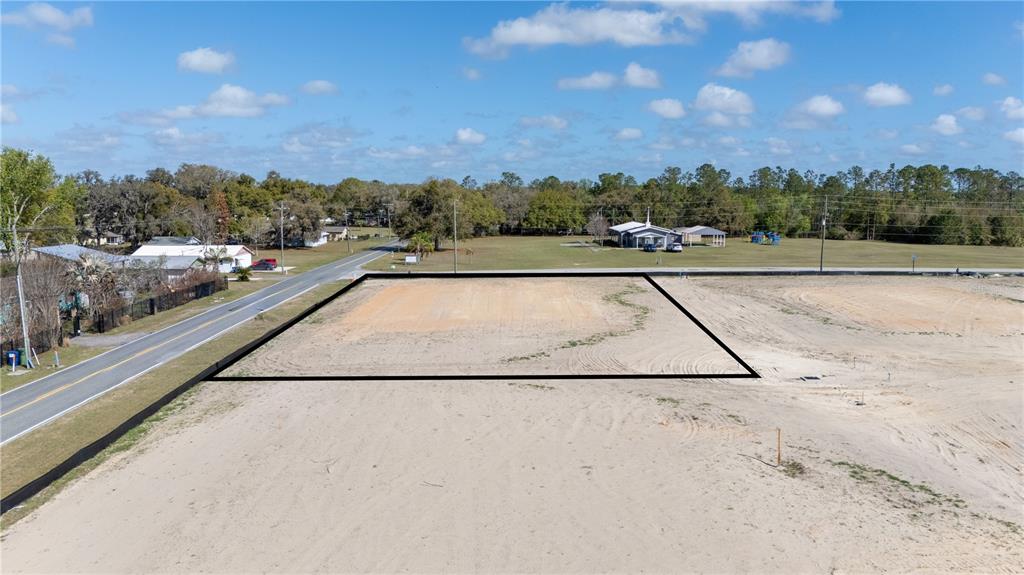 An aerial view shows a cleared, rectangular vacant lot bordered by a road and trees — 32760 DUNNE ROAD, SAN ANTONIO, FL