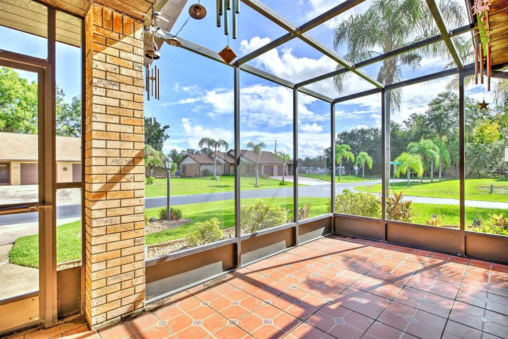A screened-in porch with tiled flooring and a brick pillar overlooking a suburban neighborhood — 2209 HIDDEN CREEK CIRCLE, SEBRING, FL