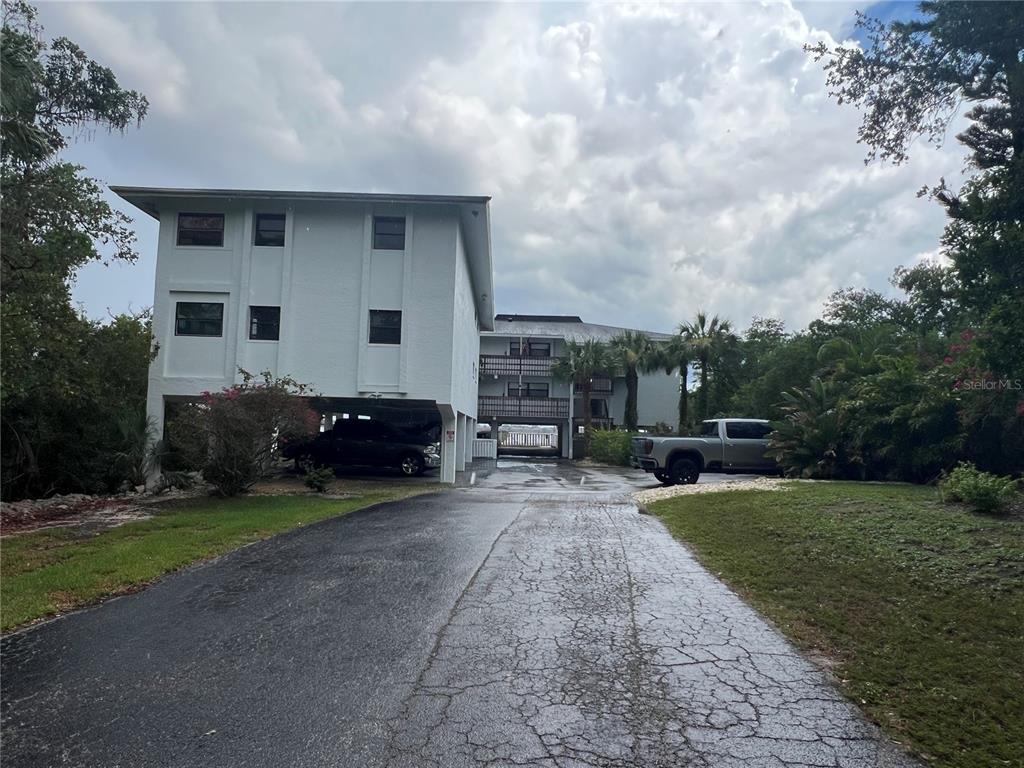 A multi-story white residential building with covered parking sits at the end of a driveway — 4403 7TH STREET E UNIT 7, ELLENTON, FL
