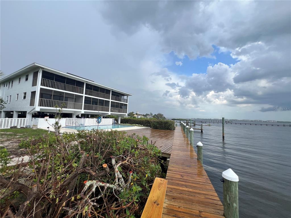 A multi-story building with a pool and wooden dock overlooking a large body of water — 4403 7TH STREET E UNIT 7, ELLENTON, FL