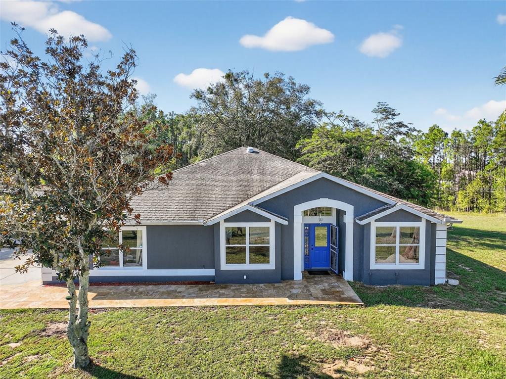 A gray, single-story house with a blue front door and a stone patio — 14520 LOST LAKE ROAD, CLERMONT, FL