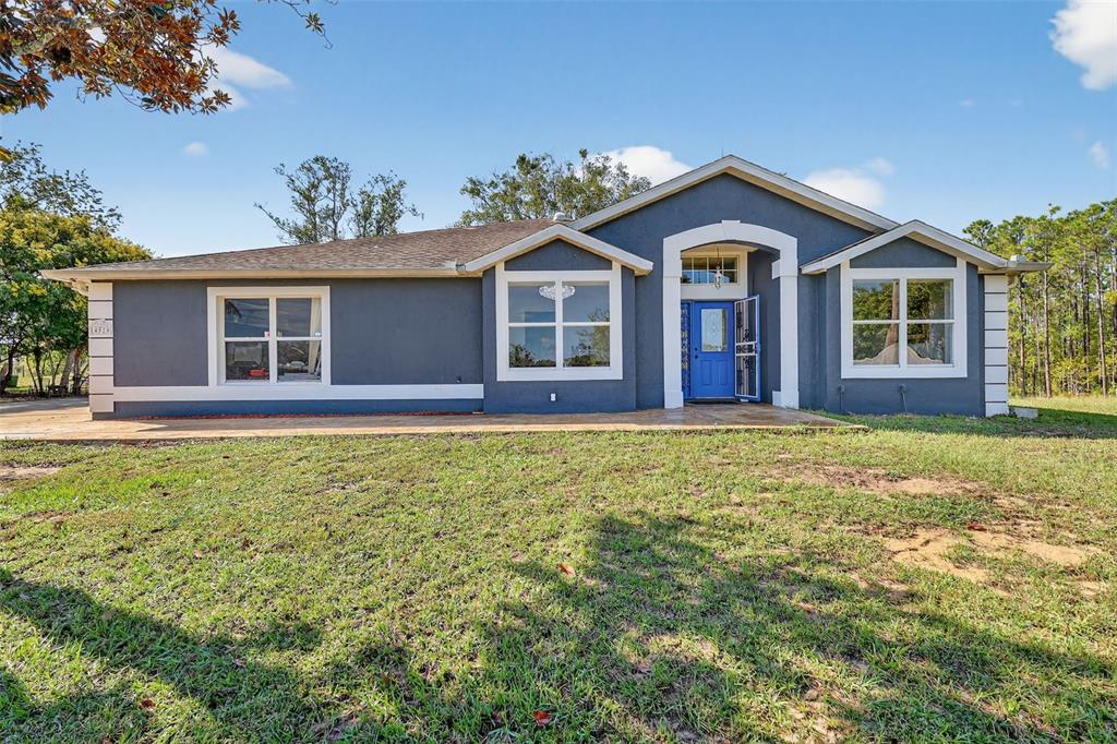 A single-story house with dark blue stucco siding, white trim, and a blue front door — 14520 LOST LAKE ROAD, CLERMONT, FL