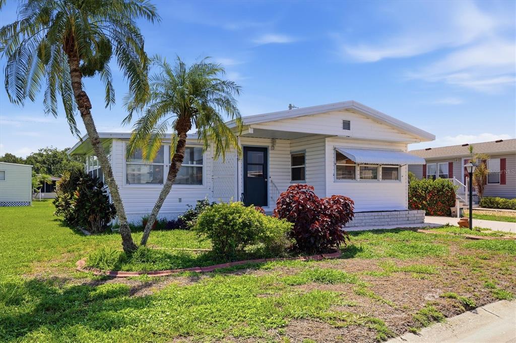 A white mobile home with a dark door and palm trees in the front yard — 1208 44TH AVENUE DRIVE E, ELLENTON, FL