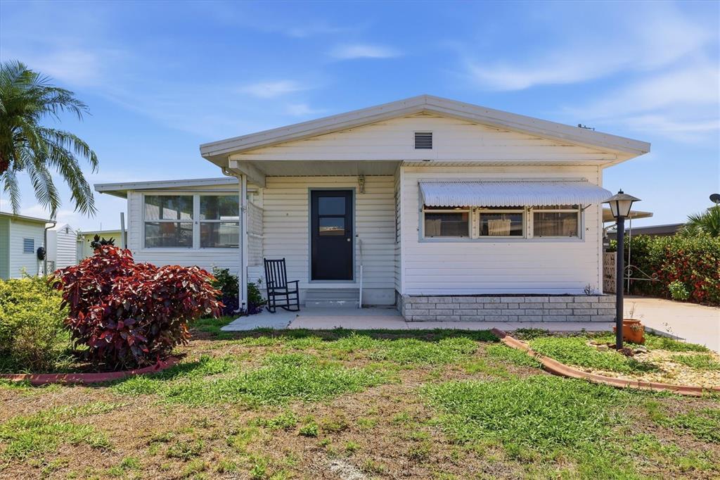 A white single-story manufactured home features a dark front door and a small front yard — 1208 44TH AVENUE DRIVE E, ELLENTON, FL