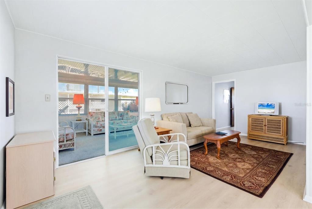A living room with light wood flooring, a beige sofa, and a sliding glass door — 1208 44TH AVENUE DRIVE E, ELLENTON, FL