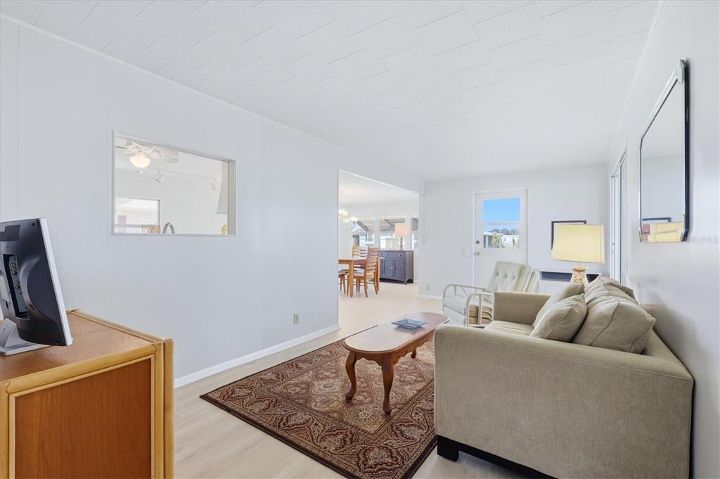 A living room with a beige sofa, patterned rug, and a view into the dining area — 1208 44TH AVENUE DRIVE E, ELLENTON, FL