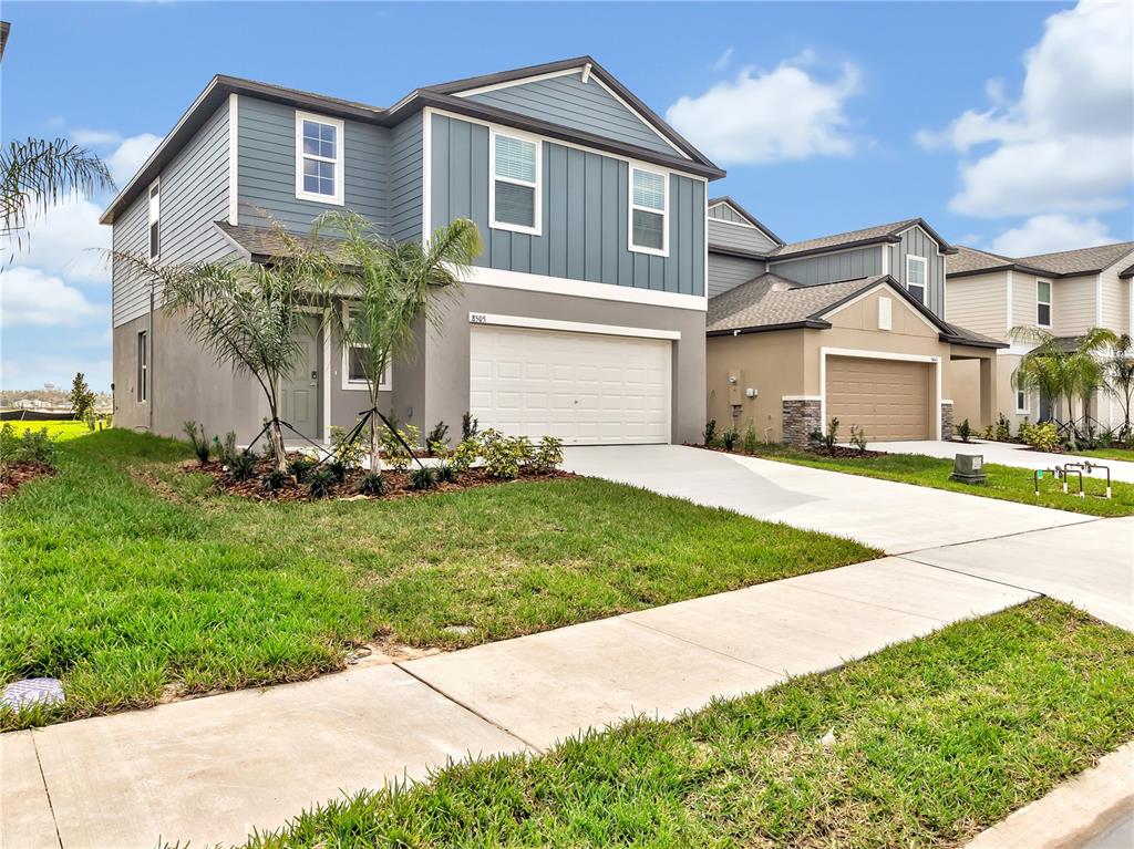 A two-story house with blue siding, a white garage door, and a concrete driveway — 8505 BELLA MAR TRAIL, PARRISH, FL