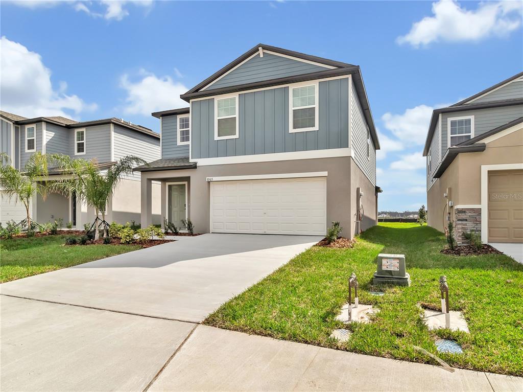 A two-story suburban house features a blue-sided upper level, a white garage, and a driveway — 8505 BELLA MAR TRAIL, PARRISH, FL
