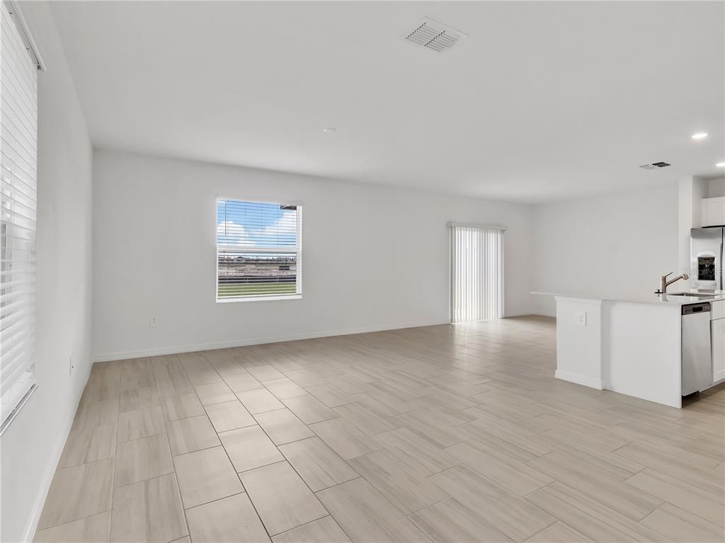 An open-concept living area features light-colored tile flooring, white walls, and a kitchen island — 8505 BELLA MAR TRAIL, PARRISH, FL